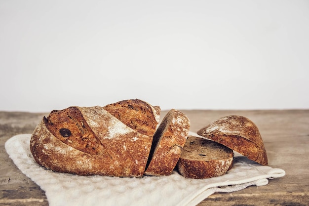 Brown fresh bread with seeds are cut into pieces on old wood background. Copy, empty space for text