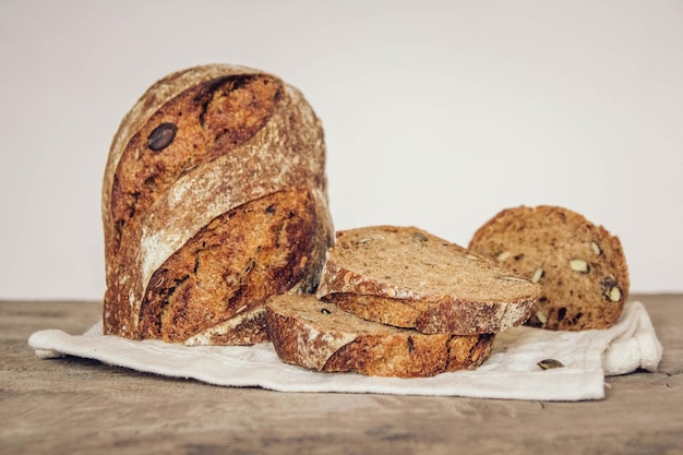 Brown fresh bread with seeds are cut into pieces on old wood background. Copy, empty space for text