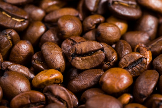 Brown freshly roasted coffee beans on a wooden table, closeup of seeds for making a drink with caffeine