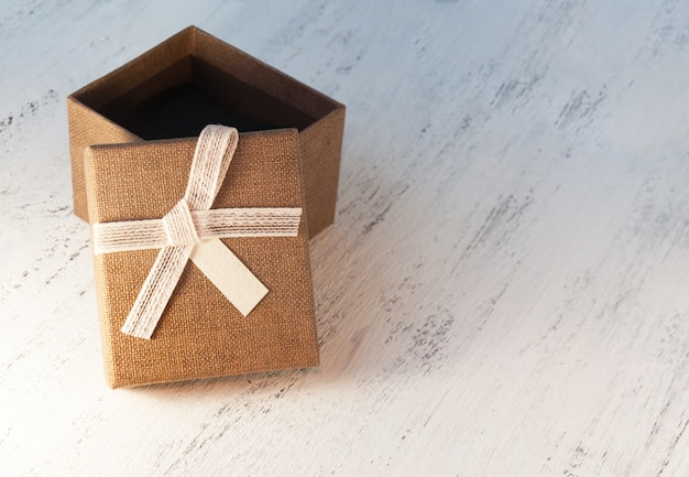 A brown gift box and a beige ribbon with a tag on a light background. A Christmas gift.Toning and blur.