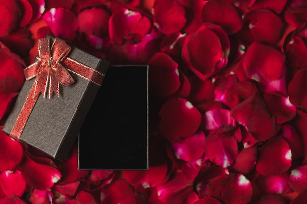 Photo brown gift box placed on red rose petals top view, valentine's day theme