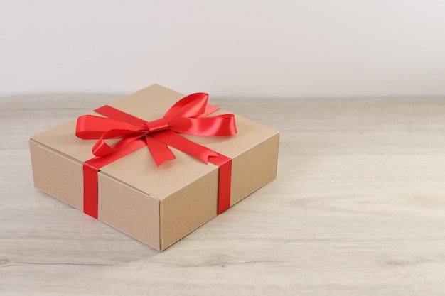 Brown gift box and red ribbon on wooden table