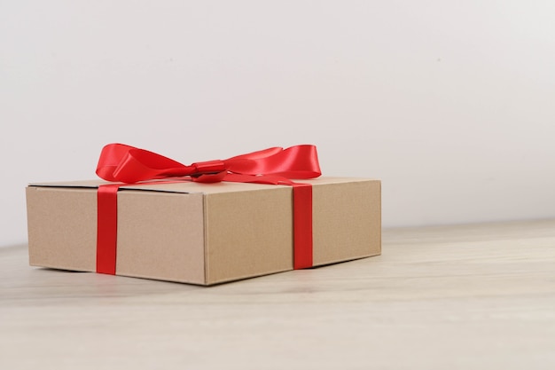 Brown gift box and red ribbon on wooden table