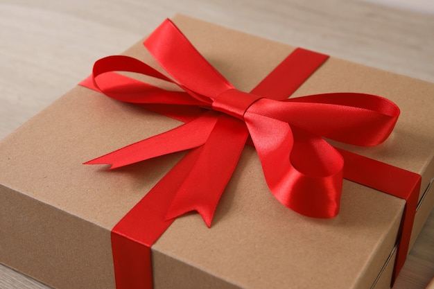 Brown gift box with red ribbon on wooden table