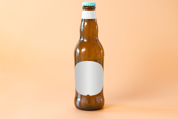 A brown glass bottle of beer with a white blank label on an\
orange background cool golden drunk fluid gold brewed alcoholic\
refreshing pub chill brand product bottle