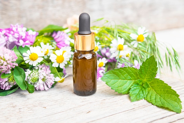 Brown glass bottle with body care cosmetic product and wildflowers on a wooden rustic background