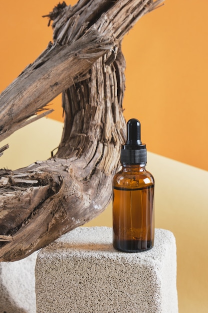 Brown glass bottle with a pipette on a concrete podium on a wooden driftwood background, brown background copy space natural cosmetic concept