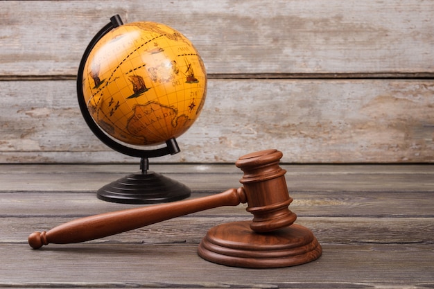 Photo brown globe with gavel on wood.