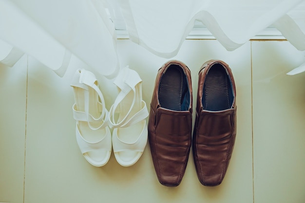 Brown groom Shoes and White bride shoes place on the floor