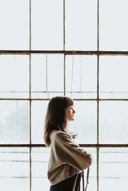 写真 窓際に立っている茶髪の女性