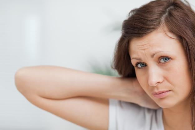 Brown-haired girl placing her hand on her neck