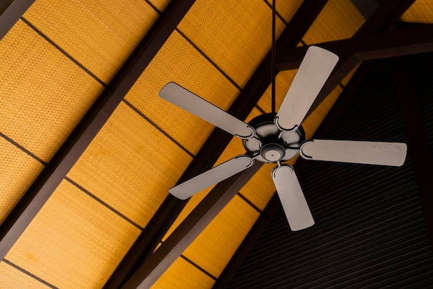 Brown indoor ceiling fan on an exposed wooden support beam with a decorate wooden ceiling in the hall of living room of a contemporary home interiorhome interior design concept