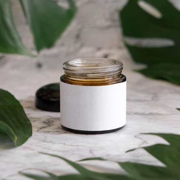 Brown jar and monstera leaves on marble table close up Brand packaging mockup