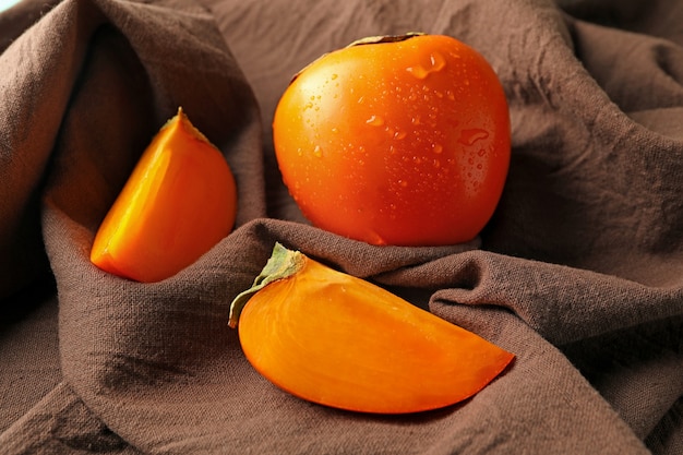 Brown kitchen towel with fresh ripe persimmon