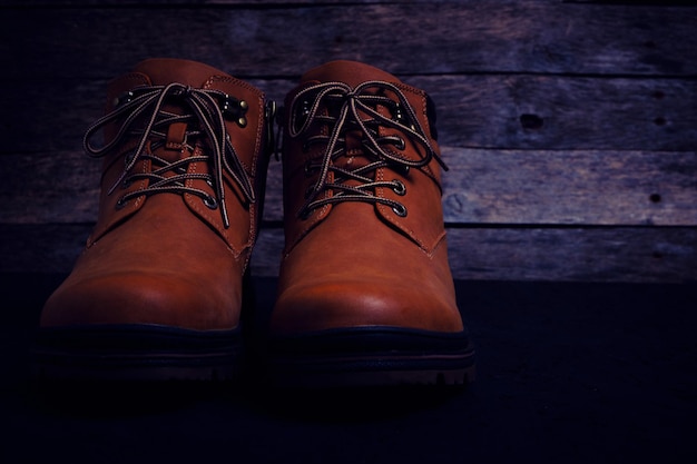 Brown, laced boots on an old wooden, rustic background.