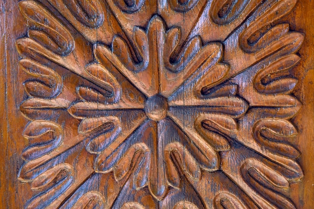 Brown lacquered flower with petals carved in wood on the door