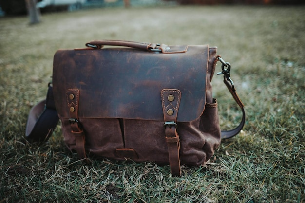 brown leather bag in a green grassy field