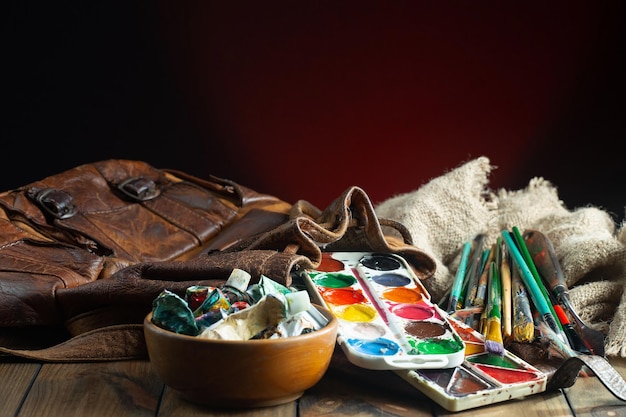 A brown leather bag with paint brushes and a brown leather bag.