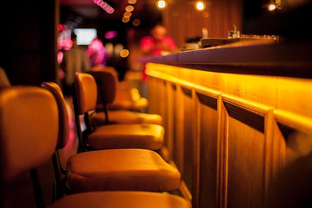 Brown leather chairs near the wooden bar in the bar, restaurant. Blurred image.