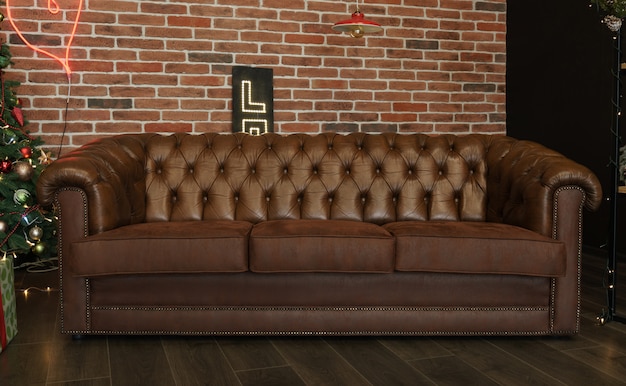 Brown leather couch near a brick wall