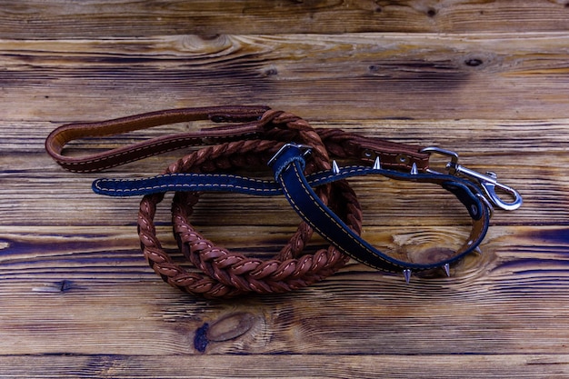 Brown leather dog leash and collar, slicker brush glove on wooden background