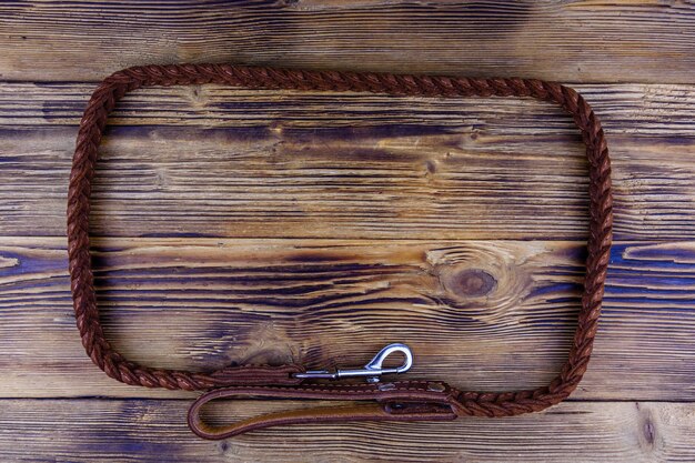 Brown leather dog leash on a wooden background. Top view