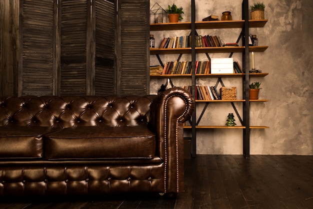 Brown leather sofa in an interior room with a bookcase.