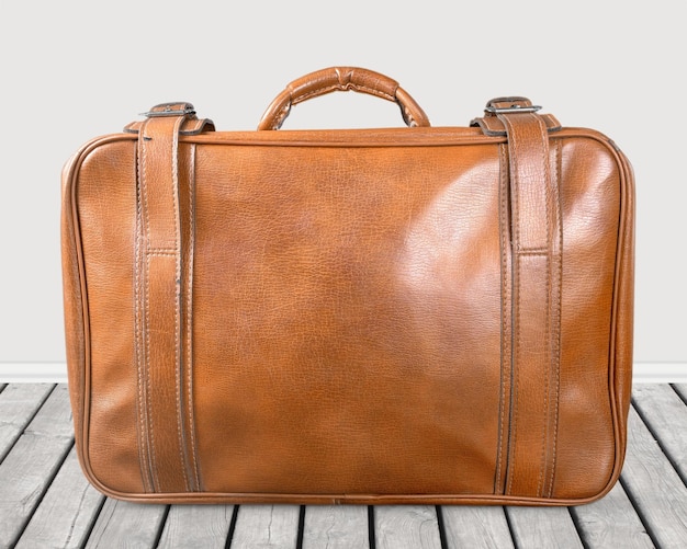 Brown leather vintage suitcase on wooden floor