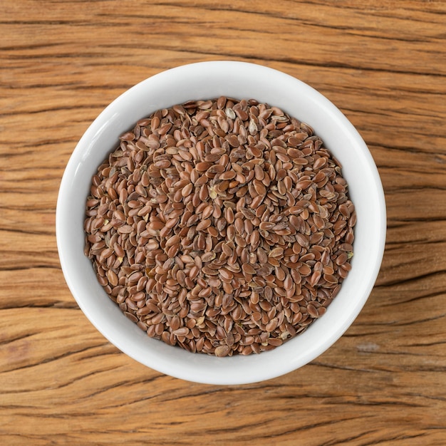 Brown linseed on a bowl over wooden table.