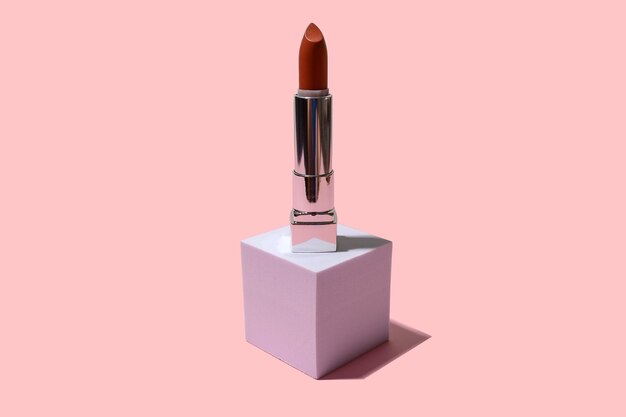 Brown lipstick on a square white podium With black shadow On a pink background