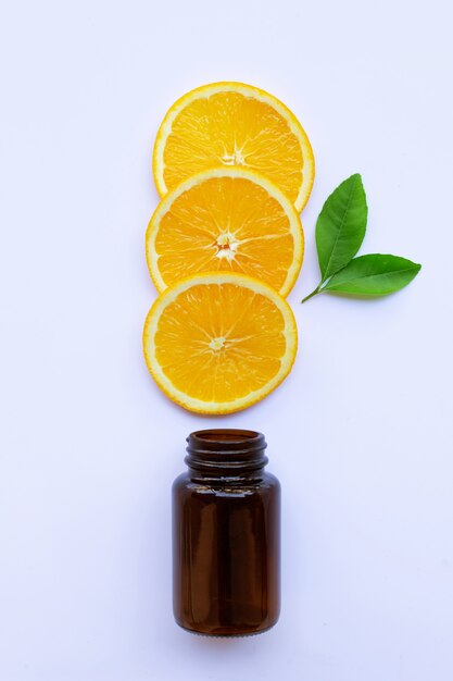 Brown medicine glass bottle with orange fruit  slices and green leaves on white 