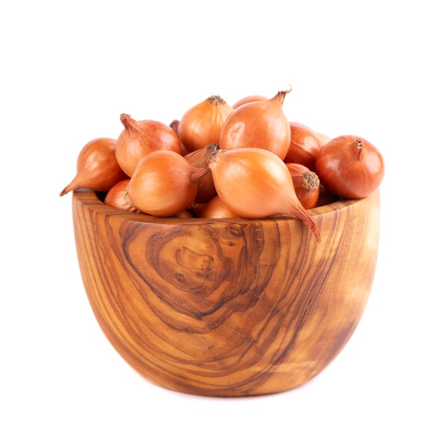 Brown mini onions in wooden bowl isolated on a white background Raw onion bulbs for cultivation French onion