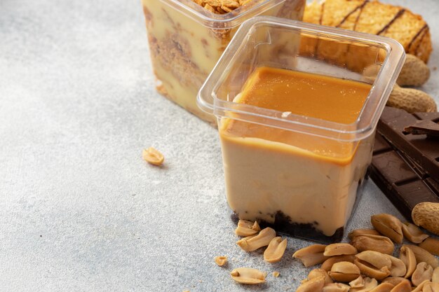 Brown mousse cream dessert in plastic transparent box on grey surface