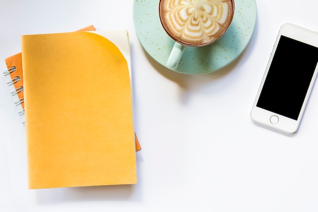 Brown notebook and  coffee with smartphone on isolated background.