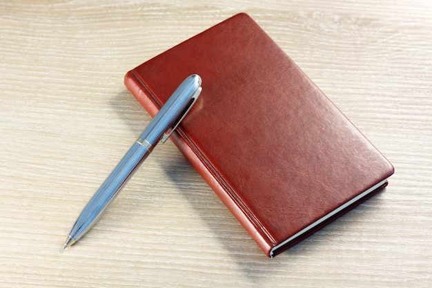 brown notebook with pen on desktop