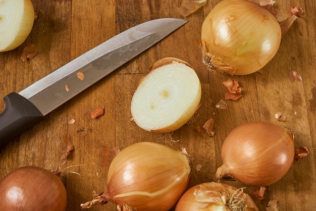 Brown onions cut by a chefs knife on a wooden surface.