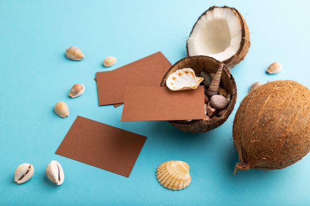 Brown paper business card with coconut and seashells on blue pastel background. Side view, 