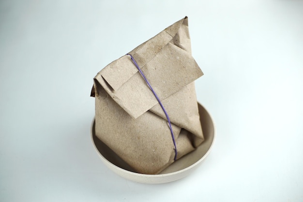 A brown paper wrapped rice bag in a bowl with a purple rubber band