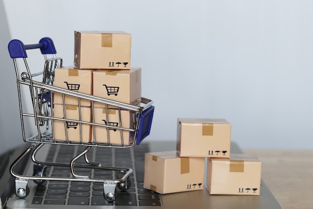 Brown parcel box and Model miniature shopping cart on computer keyboard for online shopping