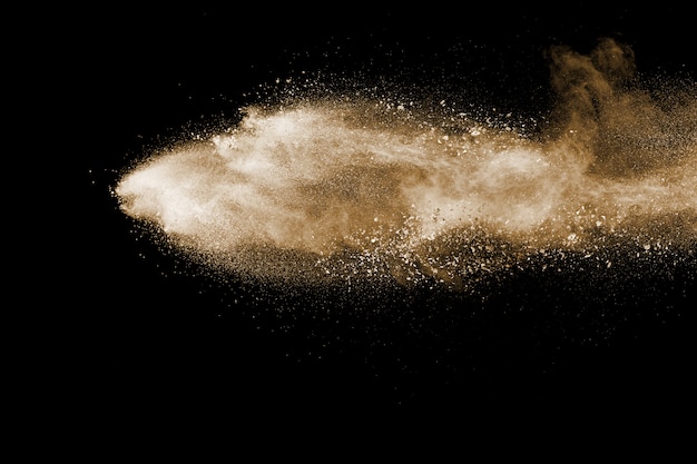 Brown particles splattered on black background. Brown dust splashing.