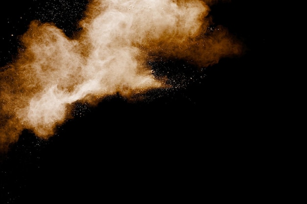 Brown particles splattered on black background Brown dust splashing