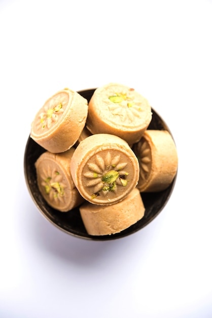 Brown Pera or pedha is an indian sweet made using  khoa, sugar and traditional flavorings, including cardamom seeds, pistachio nuts. served in a bowl or plate. selective focus