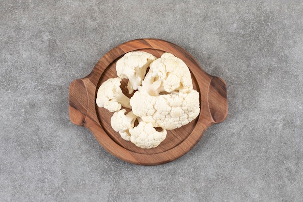 A brown plate full of ripe fresh cauliflower cut into small pieces .