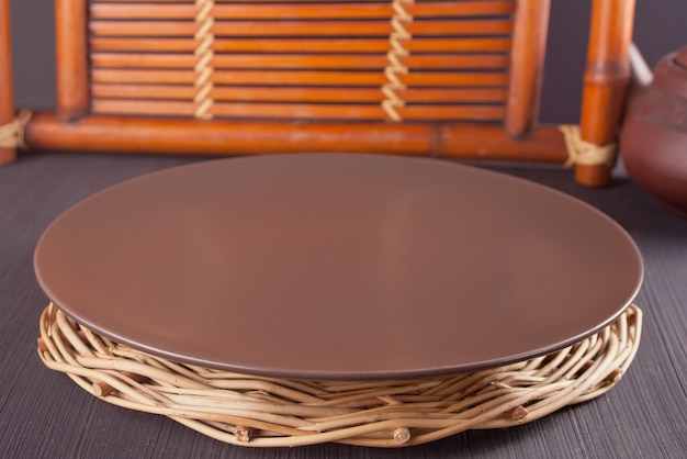 Brown plate on the wooden old table. Table setting. Oriental theme.