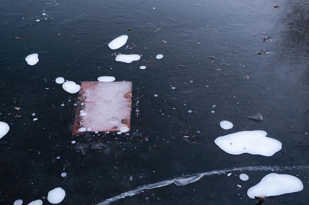 Brown plywood with screw submerged in river ice with white air bubbles Abstract background