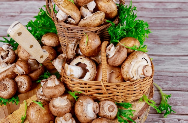 Brown portobello mushrooms in wicker wooden basket with grass decoration.