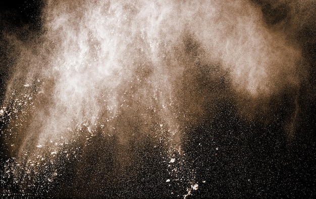 Brown powder explosion on black background.