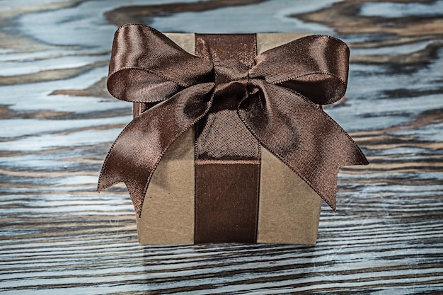 Brown present box with tied bow on wooden background