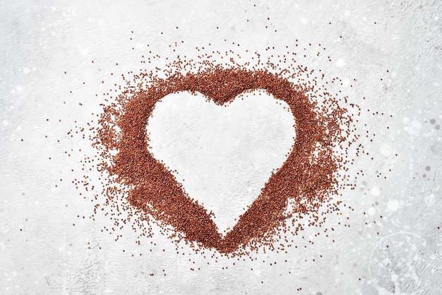 Brown quinoa Organic cereals In the form of a heart On a gray stone background Top view