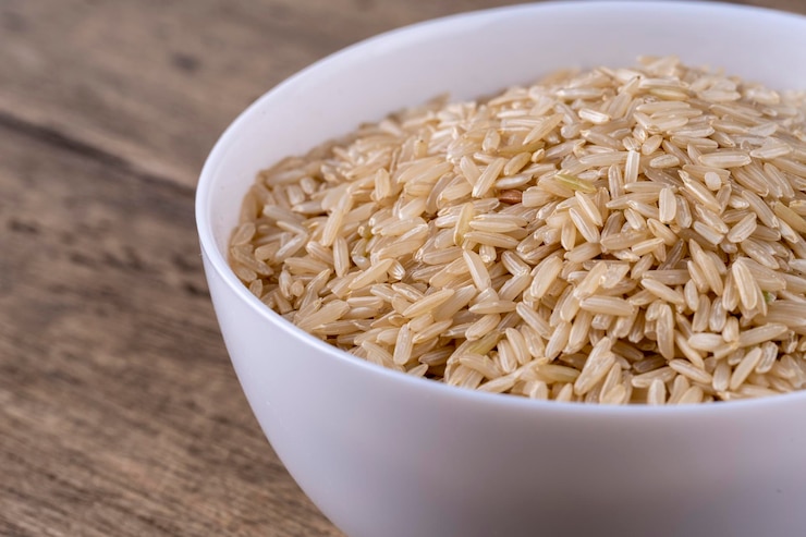Photo brown raw rice groats in white bowl isolated on wooden background